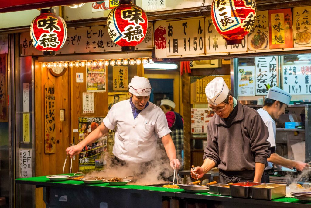 Men cook traditional Japanese street food in Osaka Japan